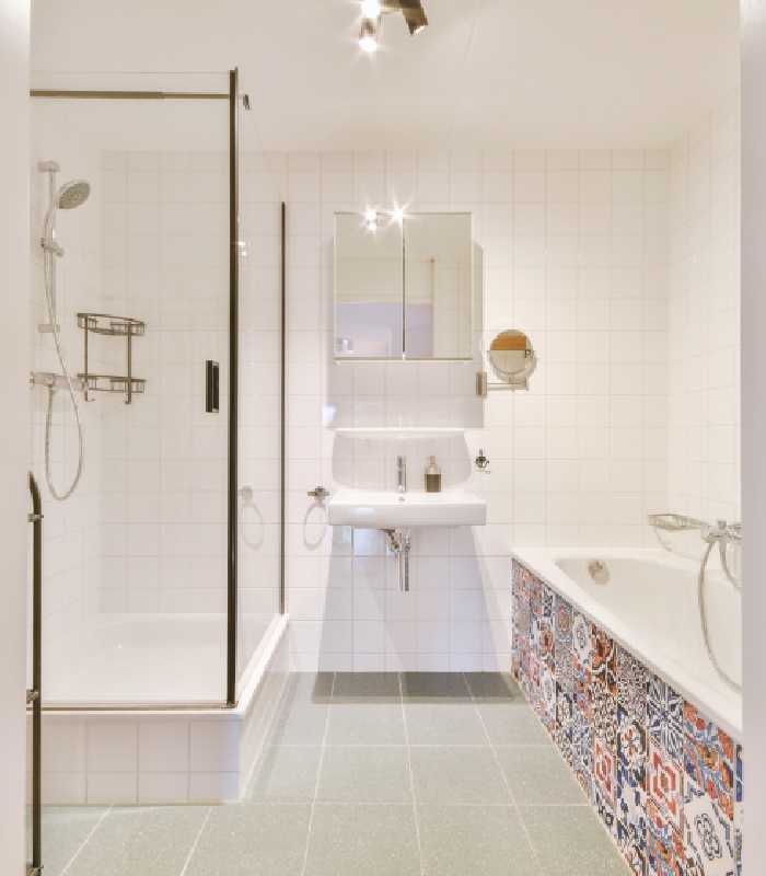 Salle de bain rénovée avec carrelage mural blanc et faïence décorative autour de la baignoire